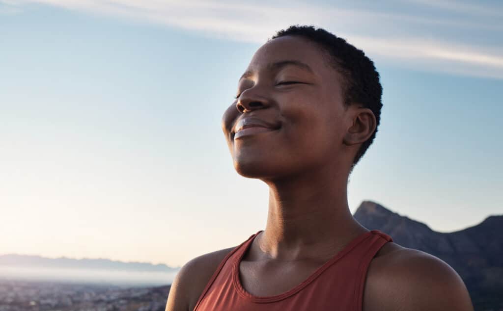 The Language of Breath fitness, calm and breathing of woman outdoor in nature, mountains and blue sky background for yoga wellness, meditation and zen energy. face of girl breathing for peace, freedom and mindfulness